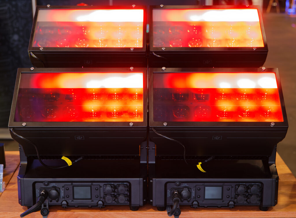 4 warm toned lights on a wooden table illuminating a lit room through frosted glass. 